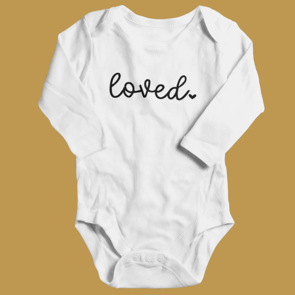 White long sleeve baby grow with Loved printed in black script, laid flat.